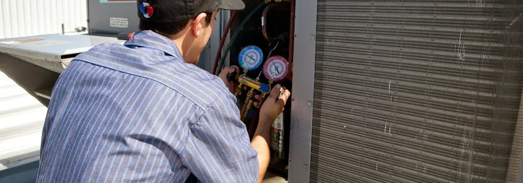 HVAC technician servicing a condenser unit in Machesney Park
