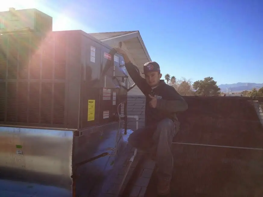 HVAC technician performing AC Tune-Up on a rooftop unit in Machesney Park
